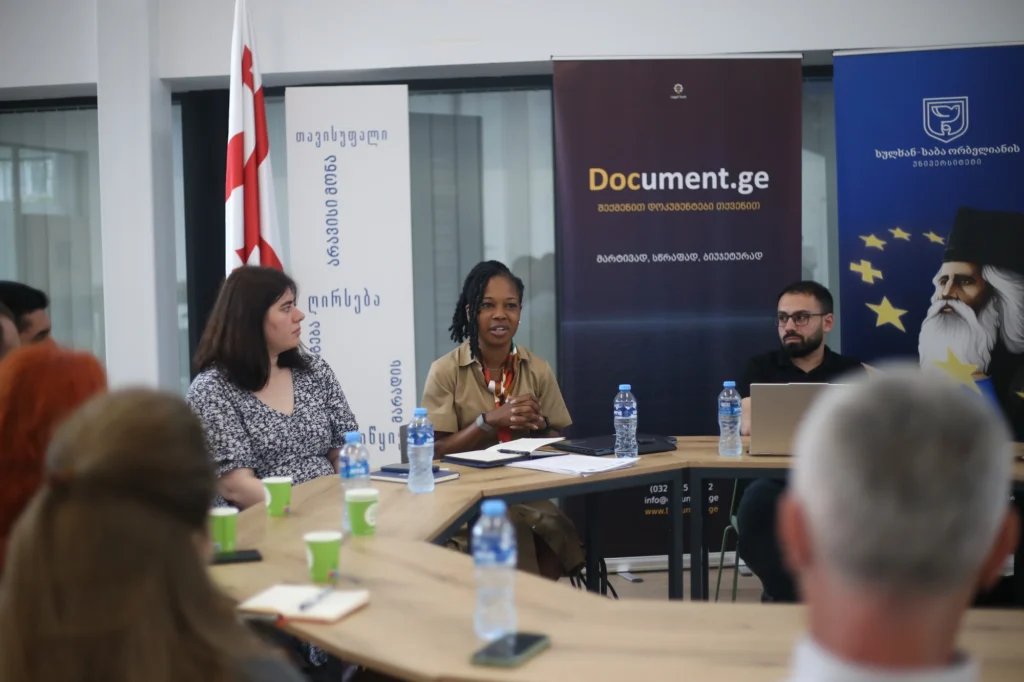 Participants seated around a table during a working session on AI litigation case law, with Document.ge and Sulkhan-Saba Orbeliani University banners behind them.