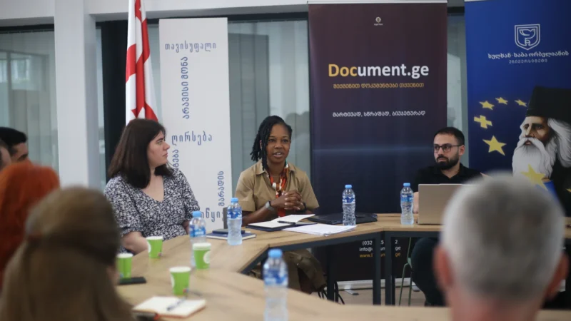 Participants seated around a table during a working session on AI litigation case law, with Document.ge and Sulkhan-Saba Orbeliani University banners behind them.
